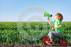 Child shouting through loudspeaker against blue summer sky