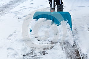 Child shoveling and removing snow in front of his house in the suburb