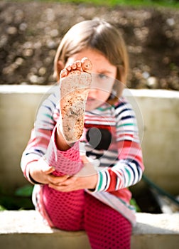 Child is showing dirty feet from playing in mud