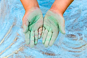 Child showing green hands with chalk