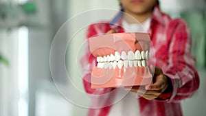 Child showing jaw model, dental services for children, prevention of caries