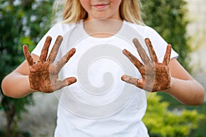 The child shows his hands in the dirt