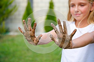 The child shows his hands in the dirt