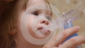 Child is sick and breathes through an inhaler. Toddler treats flu by inhaling inhalation vapor. little girl treated with