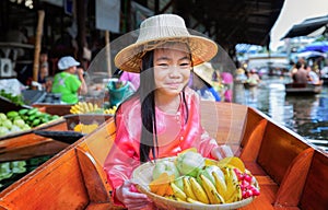 Child sit on the boat and hold the fruit basket