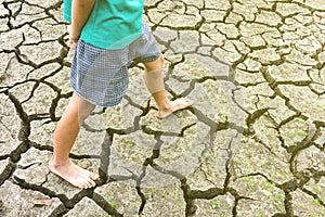 Child sit on cracked earth in the arid