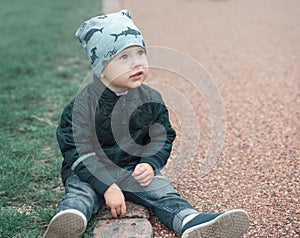 Child sits on ground and looks away