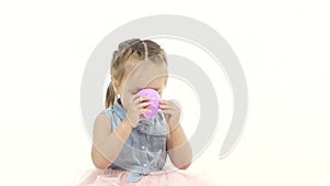 Child sits on a pillow and drinks tea. White background. Slow motion