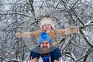 Child sits on the shoulders of his father. Father giving son ride on back in park. Merry Christmas and Happy new year