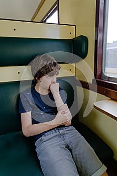 Child sitting alone and looking out the window serious staring face thinking concept