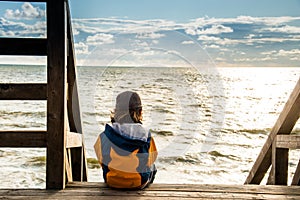 Child sitting alone and watching the sea water