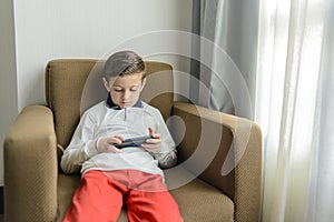 Child sitting in an armchair playing with a smartphone