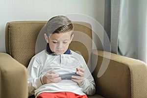 Child sitting in an armchair playing with a smartphone