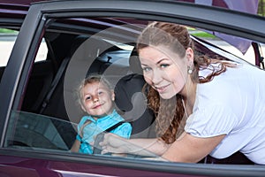 Child sitting in baby car seat and mother helping