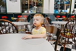 Child sitting in cafe and waiting pizza.