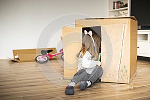 Child sitting in a cardboard playhouse