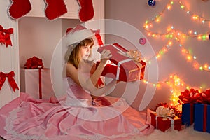 Child sitting with Christmas gifts in their hands near fireplace