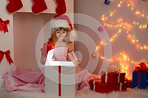 Child sitting with Christmas gifts in their hands near fireplace