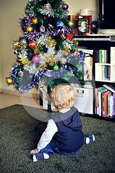 A child sitting by a christmas tree