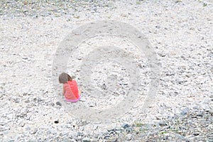 Child sitting in dried river bed in Middle Asia Kazakhstan among the white stones lonely