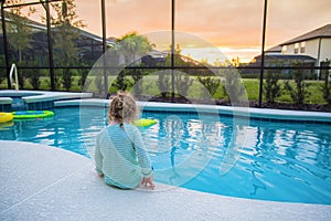 Child sitting on the edge of a swimming pool on a warm summer day photo