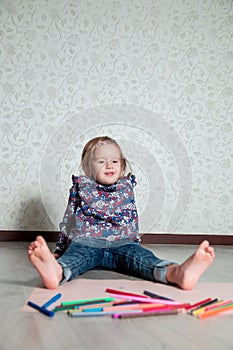 Child sitting on the floor near crayons and paper. Little girl drawing, painting. Creativity concept. Happy, smiling.