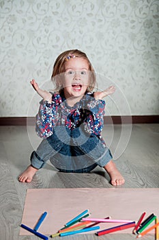 Child sitting on the floor near crayons and paper. Little girl drawing, painting. Creativity concept. WOW. oops