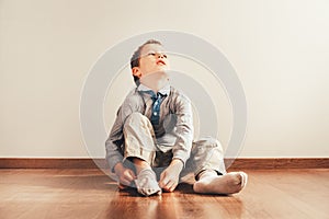 Child sitting on the floor putting on his socks with an expression of effort, concept of autonomy