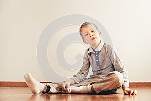 Child sitting on the floor putting on his socks with an expression of effort, concept of autonomy