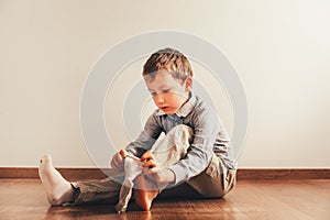 Child sitting on the floor putting on his socks with an expression of effort, concept of autonomy