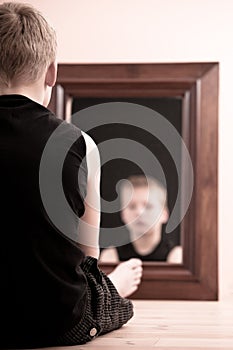 Child sitting on floor staring into mirror