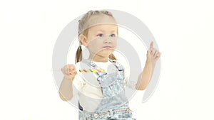 Child is sitting on a green chair, holding a candy. White background. Slow motion