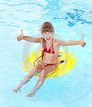 Child sitting on inflatable ring thumb up.