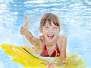 Child sitting on inflatable ring thumb up.