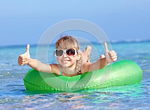 Child sitting on inflatable ring thumb up.