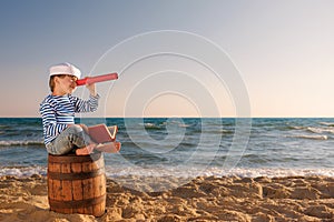 Child sitting on old barrel on the beach