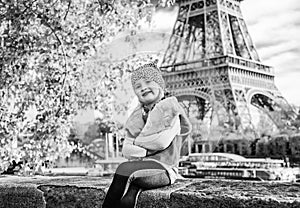 Child sitting on parapet on embankment near Eiffel tower