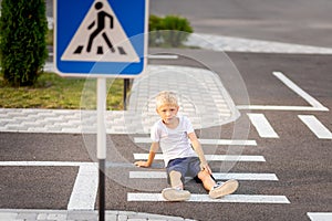 A child is sitting on the road at a pedestrian crossing and holding his leg, traffic rules for children