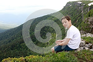 Child sitting on rock on Lago-Naki plateau in summer