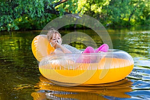 The child is sitting in a rubber ring and talking on a mobile phone