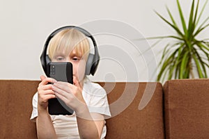 Child sitting on sofa and using smartphone. Internet addiction concept