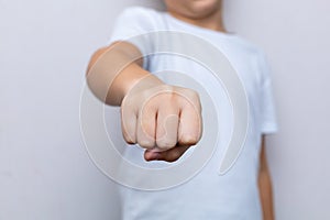 A child is sitting at a table, folding his hands neatly