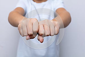 A child is sitting at a table, folding his hands neatly