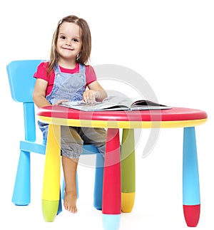 Child sitting at the table and reading a book