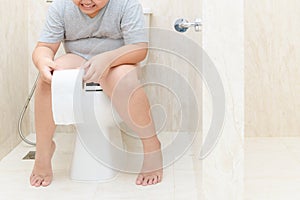 Child sitting in toilet and holding tissue roll
