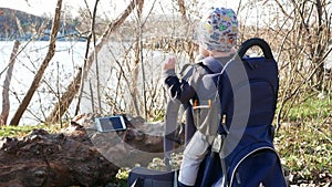 A child sitting in a tourist backpack watches a cartoon