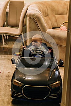 The child is sitting in a toy car, playing, trying to go