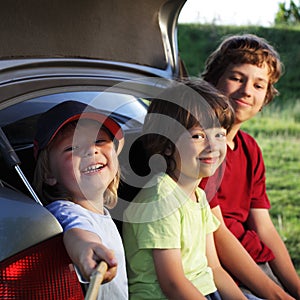 Child sitting in the trunk of a car on nature