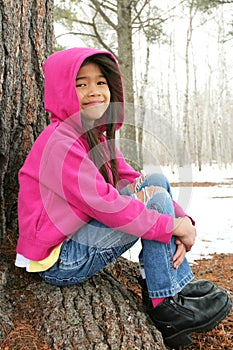 Child sitting under tree in winter