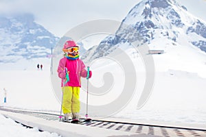 Child on ski lift in snow sport school in winter mountains